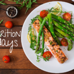 The image displays a white plate with colorful looking food on it- bright green asparagus, pink baked salmon, and cherry red tomatoes. This is an example of a nutritious meal.