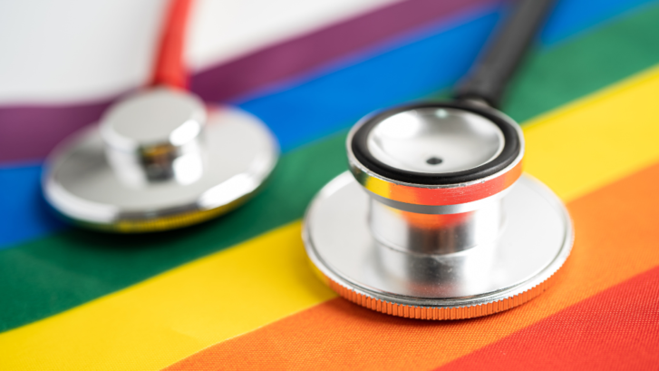 A close up image of a stethoscope on a rainbow flag to represent LGBT medical professionals